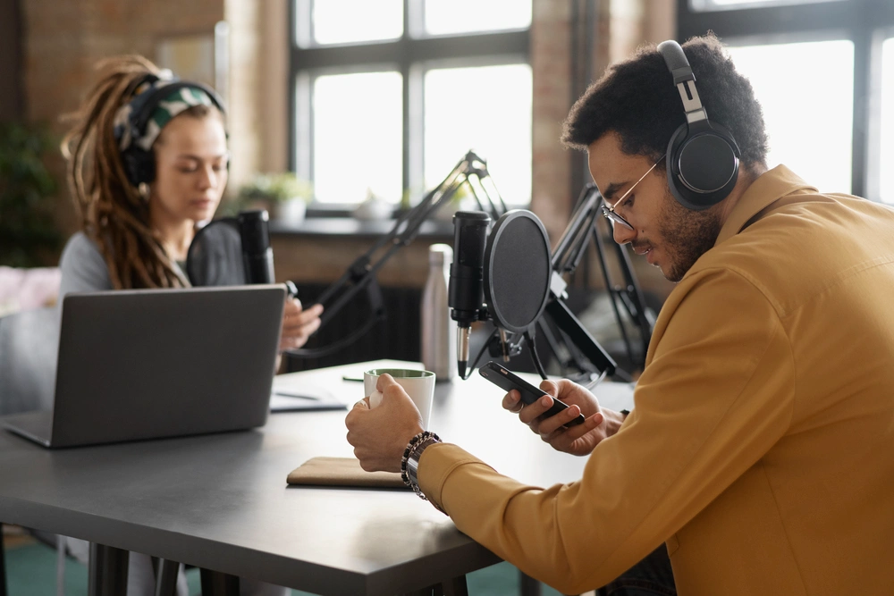 Two people recording a podcast with headphones and microphones